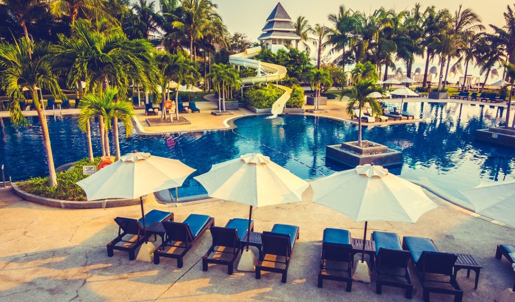 Beautiful Silhouette palm tree with umbrella and chair around luxury swimming pool in hotel resort at sunset time - Vintage Filter and Color boost Up Processing